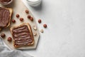 Board of bread with chocolate paste and hazelnuts on white background, closeup Royalty Free Stock Photo
