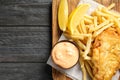Board with British traditional fish and potato chips on wooden background, top view