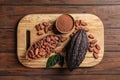 Board with cocoa pods, beans and powder on wooden table Royalty Free Stock Photo