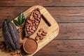 Board with cocoa pods, beans and powder on wooden table, top view with space for Royalty Free Stock Photo