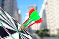 Board with color darts hitting target against blurred view of cityscape Royalty Free Stock Photo