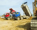 On-board dump trucks unload sand