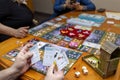 Board game concept. Board game field, many figures, dice and coins. Friends play holding cards on blurred background Royalty Free Stock Photo