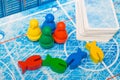 Board game and kids leisure concept - red, yellow, blue, green fish wood chips figure and playing cards in children play.