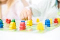 yellow people figure in hand of child. red, blue, green wood chips in children play - Board game and kids leisure concept