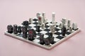 Board game, toy chess figures and chess board on pink background Royalty Free Stock Photo