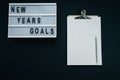 Board with `GOALS` text, notebook, pencil on black background, top view, flat lay