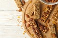 Board with granola bars and bowl with almond on wooden background, top view