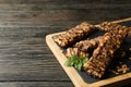 Board with granola bars on wooden background, space for text