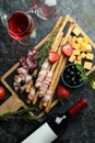 Board with grissini and snacks, and wine on black smokey background