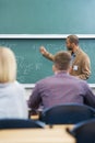 Board, lecture and professor with students in classroom for mathematics lesson at university campus. Education, learning