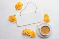Board for note, flowers and cup of coffee over white wooden back
