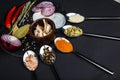 A board with onion, garlic, bay leaf, pepper and salt beside which lie spoons with various spices. Royalty Free Stock Photo