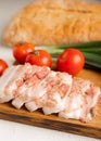 Board with pork fat, green onions, homemade bread and cherry tomatoes on a gray stone background.