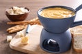 Board with pot of cheese fondue, bread and fork on table, space for Royalty Free Stock Photo