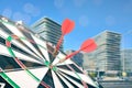 Board with red darts hitting target on blurred view of cityscape Royalty Free Stock Photo