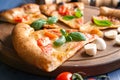 Board with slice of delicious pizza Margherita on wooden background, closeup Royalty Free Stock Photo