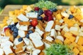 Board with sliced cheese, bread and berries for a festive buffet in the summer in the yard