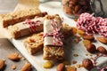 Board with tasty granola bars and nuts on background, close up