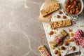 Board with tasty granola bars and nuts on gray background, top view