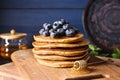 Board with tasty pancakes, blueberries and honey dipper on table Royalty Free Stock Photo