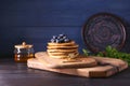 Board with tasty pancakes, honey dipper and blueberries on wooden table Royalty Free Stock Photo