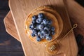 Board with tasty pancakes, honey dipper and blueberries on wooden table Royalty Free Stock Photo