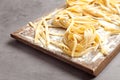 Board with uncooked egg noodles and flour on grey table Royalty Free Stock Photo