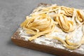 Board with uncooked egg noodles and flour on grey table Royalty Free Stock Photo