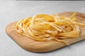 Board with uncooked egg noodles on grey table Royalty Free Stock Photo