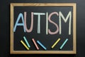 Board with word Autism and colorful chalks on black background, top view Royalty Free Stock Photo