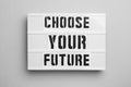 Board with words CHOOSE YOUR FUTURE on background, top view. Career concept Royalty Free Stock Photo