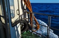 On board yacht, vessel, ship white door with red ropes in the light of sunset light in blue sea with foam