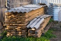 Boards, lumber, stored and covered with slate, lies in a private area in the corner of the fence