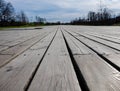 Boardwalk by the garden, wooden plank, decking, walkway, path or terrace, low angle view image of patio deck with blurred green Royalty Free Stock Photo