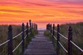 Boardwalk path leading directly to Maine east coast ocean view during stunning orange and red sunrise Royalty Free Stock Photo