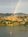 Boat in the Akaroa harbor in New Zealand, with a vibrant rainbow stretching across the sky Royalty Free Stock Photo