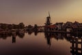 Boat anchored on a canal in Amsterdam at sunrise, windmill