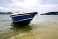boat anchored near the beach, cloudy sky and soft wave hitting the shore background. Royalty Free Stock Photo