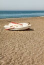 A small wooden boat used by fishermen beached on the sandy beach next to the Mediterranean Sea Royalty Free Stock Photo