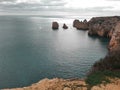 A silvering sea looks metallic under the pale cloudy skies