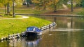 A boat on the city lake, autumn, along with cars parked on the street, white residential buildings and green grass Royalty Free Stock Photo