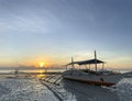 Boat close-up. Beautiful yellow-orange sunset, dawn background sky behind.Low tide on a sandy beach with small stones Royalty Free Stock Photo