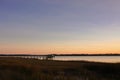 A boat dock leads out from the marsh into the waters of a river in the low country of South Carolina at sunset; copy space Royalty Free Stock Photo