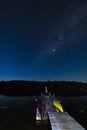 Boat dock under a starry sky as meteor streaks across the Milky