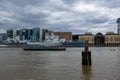 Boat docked in the river themes, military navy boat museum in sight. Cloudy sky above. Royalty Free Stock Photo
