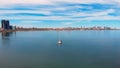 Boat floats North American Lake Ontario, urban landscape backdrop, embodying solitude. Its solitude amidst city bustle