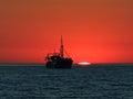 Boat in front of a sunset at the horizon