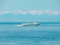 The boat at high speed goes along Lake Baikal against the backdrop of snow-capped mountains Royalty Free Stock Photo