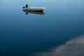 A boat and its clear symmetry reflection on the lake surface.